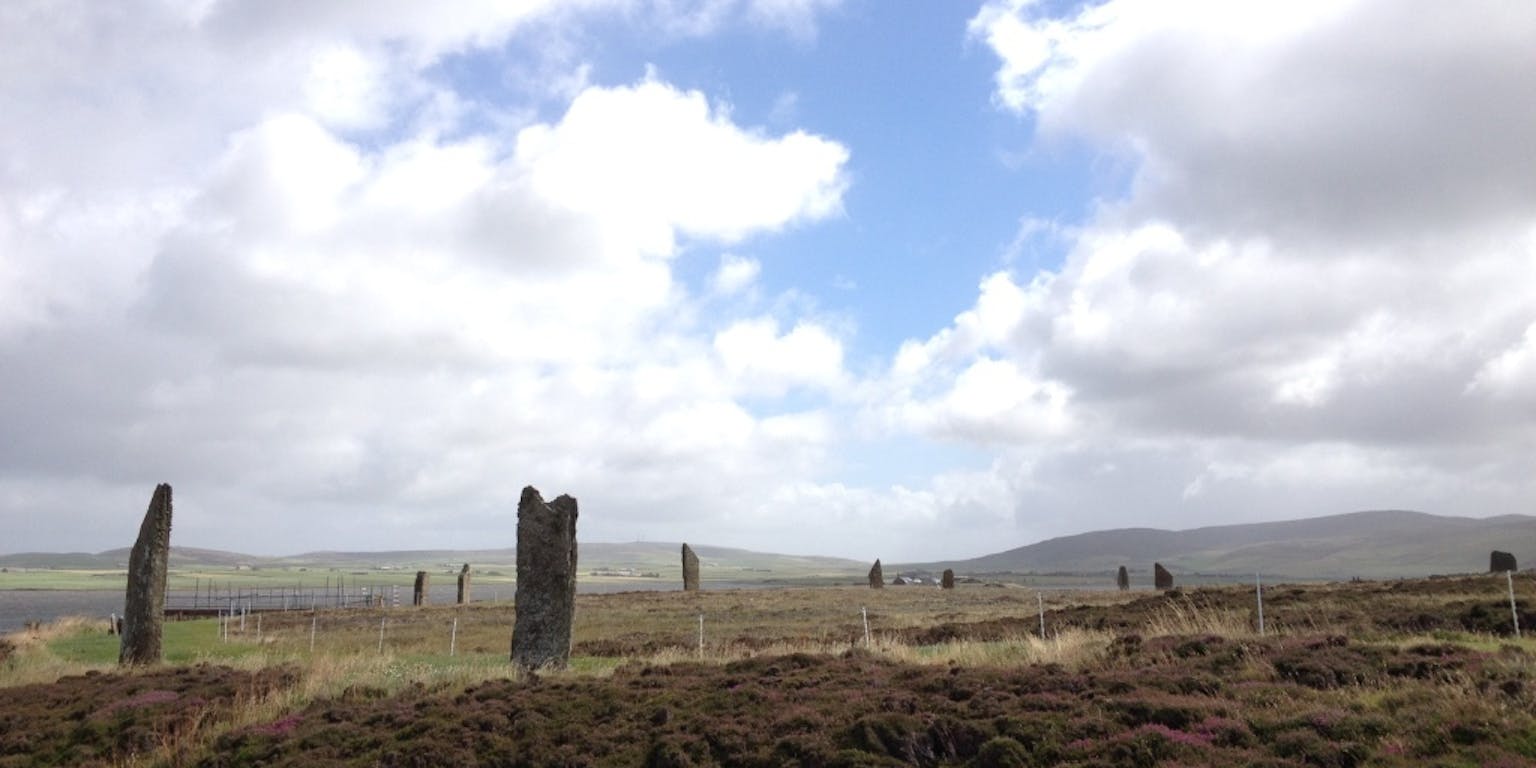 Een groep stenen pilaren in een veld met een bewolkte hemel.