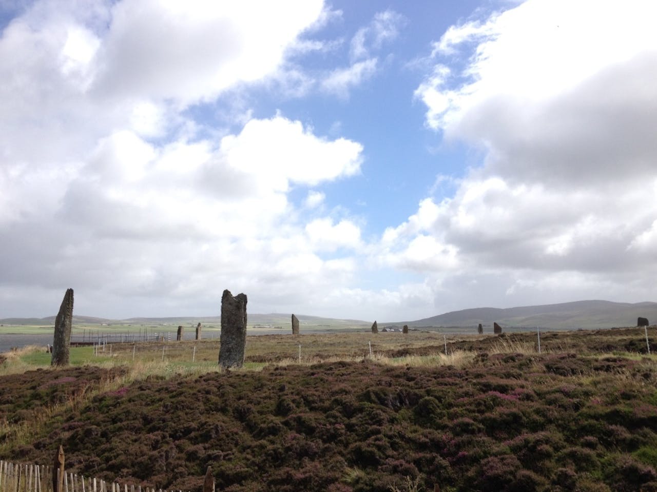 Een groep stenen pilaren in een veld met een bewolkte hemel.