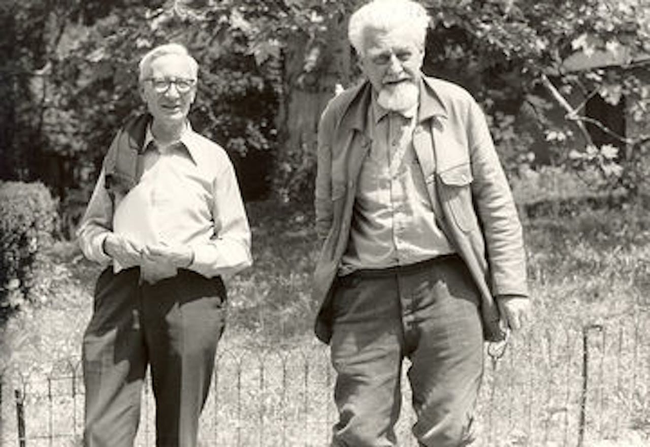 Nikolaas Tinbergen en Konrad Lorenz staan lachend naast elkaar in een tuin.