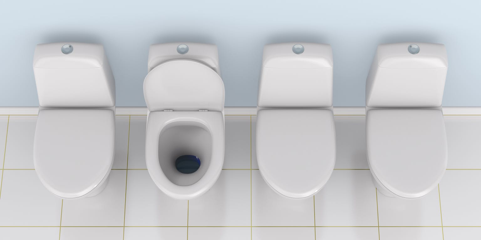Vier witte toiletpotten van boven gezien. De klep van de tweede van links staat open. Op de vloer liggen witte tegels. De muur is lichtblauw.