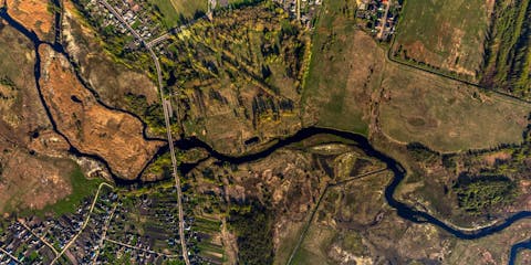 Luchtfoto van een kronkelende rivier in bewoond landschap Luchtfoto van een kronkelende rivier in bewoond landschap