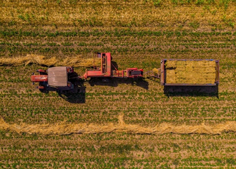 Bovenaanzicht van traktor die het gras maait op een groot weiland