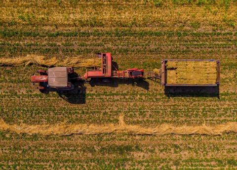 Bovenaanzicht van traktor die het gras maait op een groot weiland Bovenaanzicht van traktor die het gras maait op een groot weiland