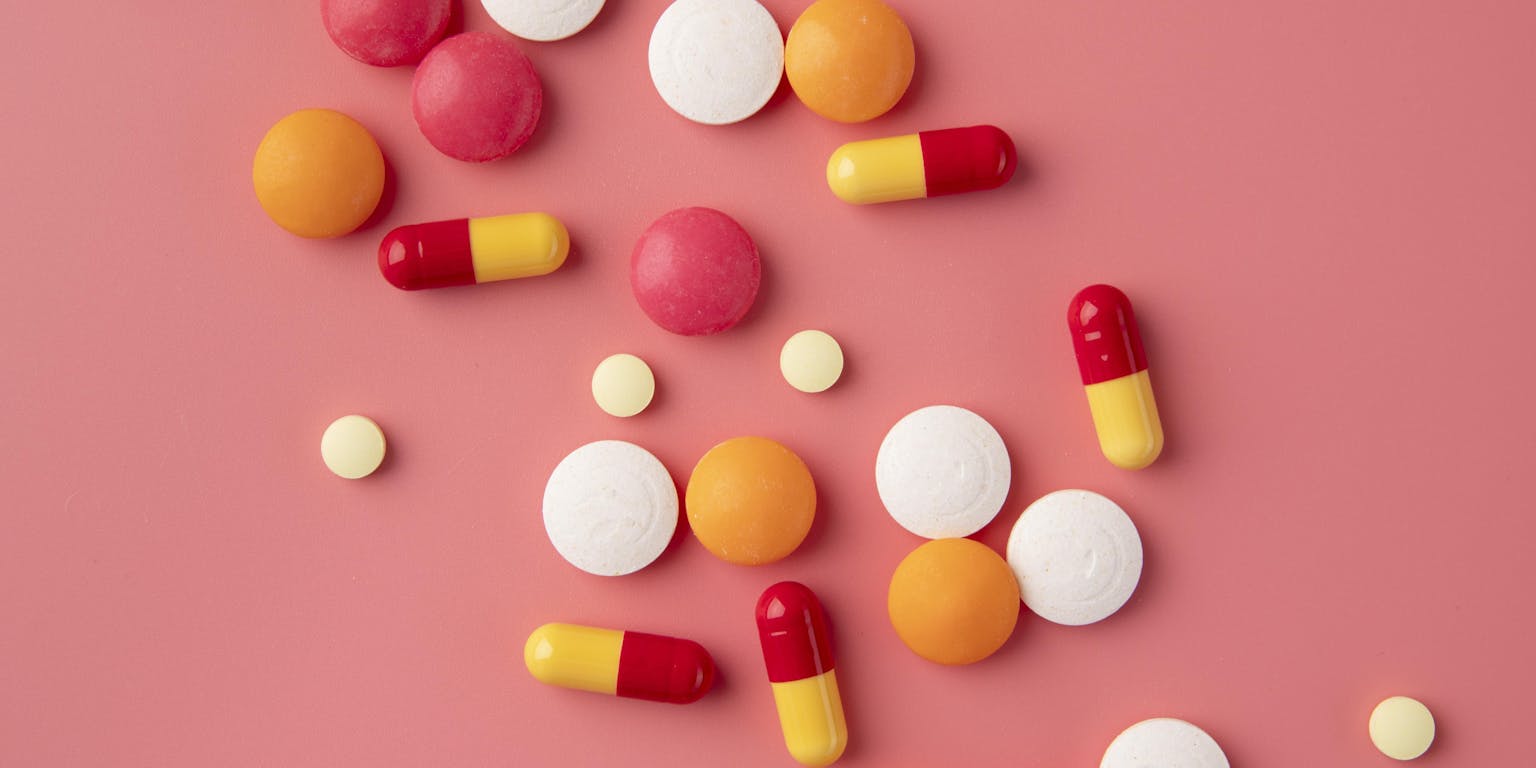 verschillende kleuren medicijnen op een roze ondergrond