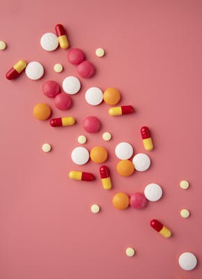 verschillende kleuren medicijnen op een roze ondergrond