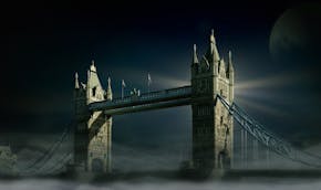 Een foto van de Tower Bridge in London. Het is donker, mistig en de maan is zichtbaar.