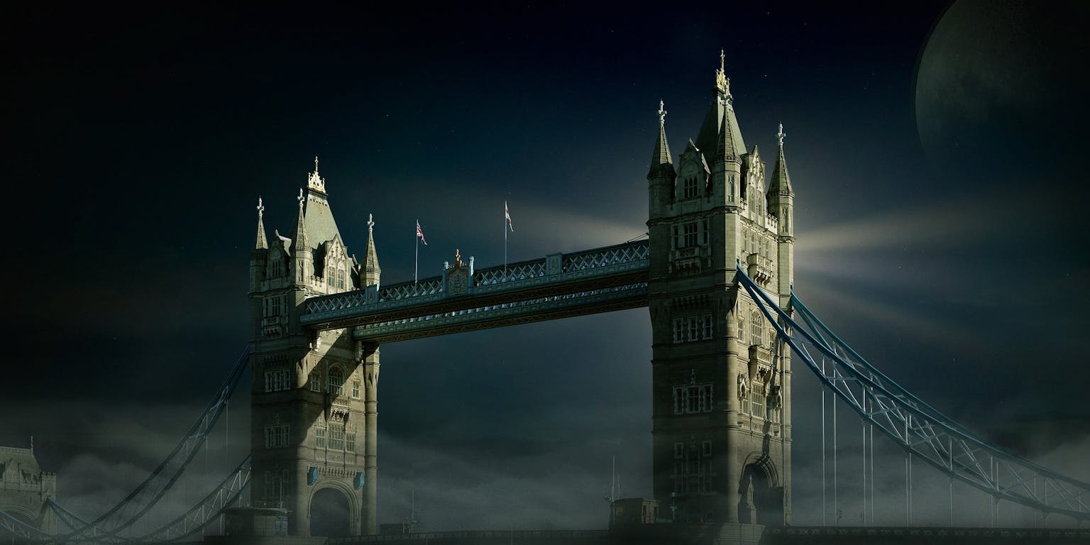 Een foto van de Tower Bridge in London. Het is donker, mistig en de maan is zichtbaar.