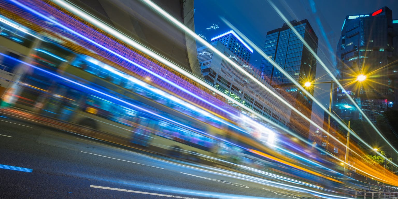 De long exposure van voorbijrijdende auto's in een stad.