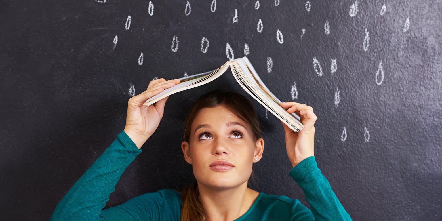 tiener schuilt met een boek voor de regen die op een krijtbord is getekend