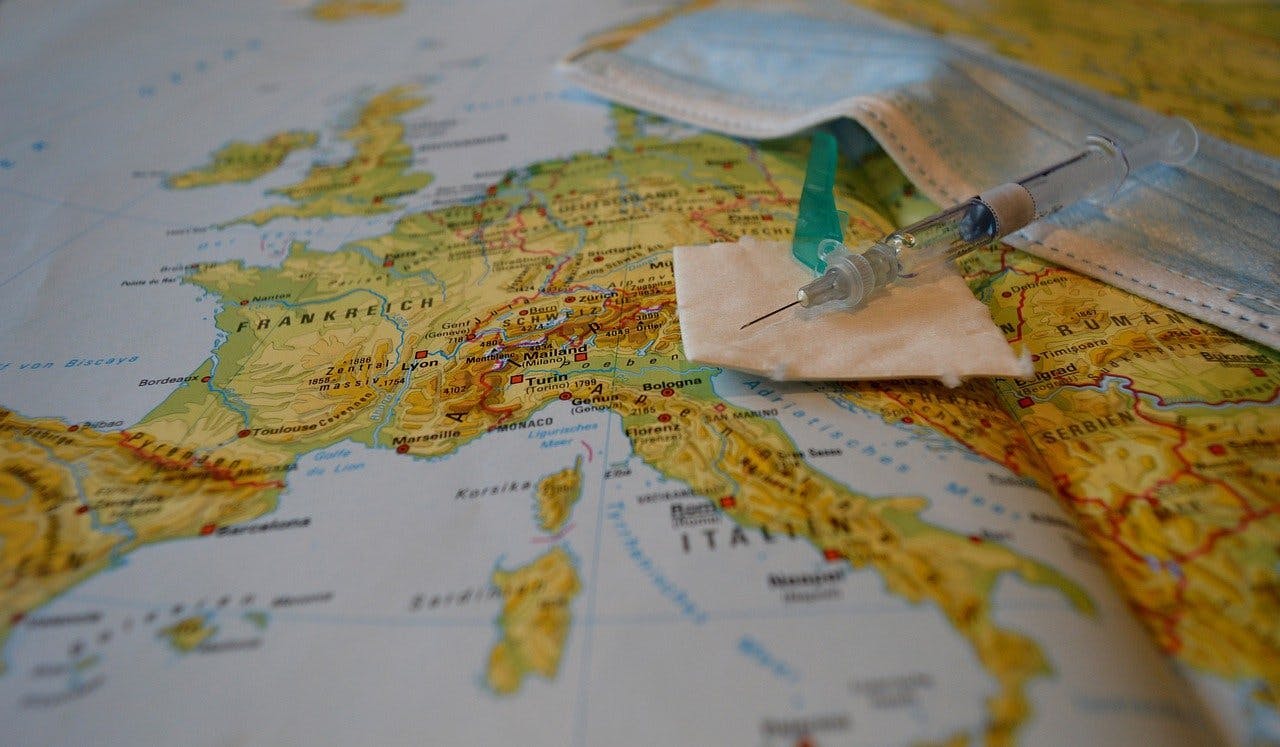 Een mondkapje en een spuit op een kaart van Europa.