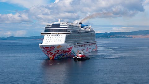 Een cruiseschip met kleurrijke boog vaart met een loodsbootje naast zich. Een cruiseschip met kleurrijke boog vaart met een loodsbootje naast zich.