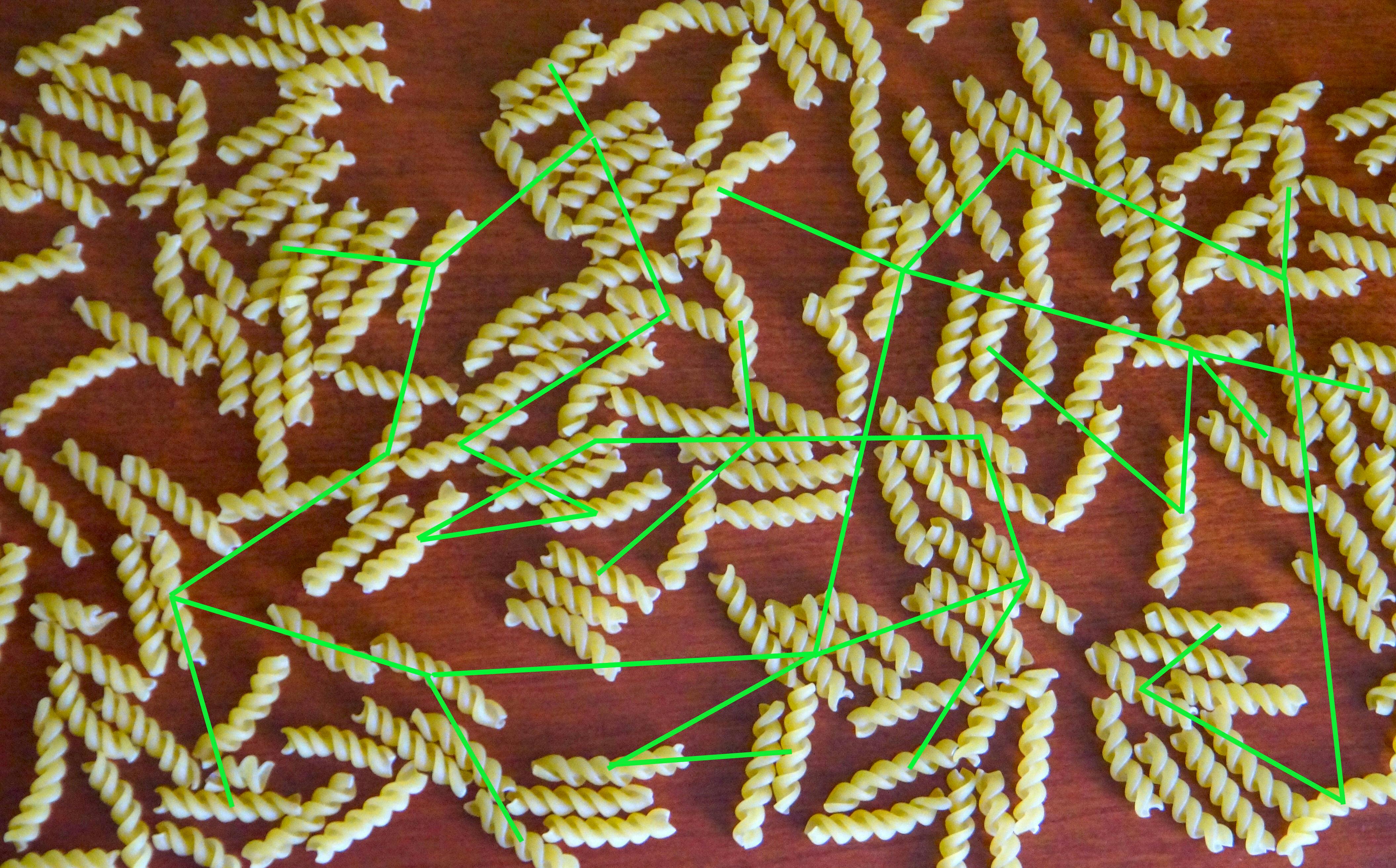 Een tafel met gedraaide pasta strengen en groene lijnen kriskras over de afbeelding. Het moet een virusreconstructie voorstellen.