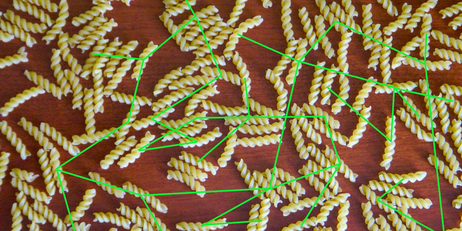 Een tafel met gedraaide pasta strengen en groene lijnen kriskras over de afbeelding. Het moet een virusreconstructie voorstellen.