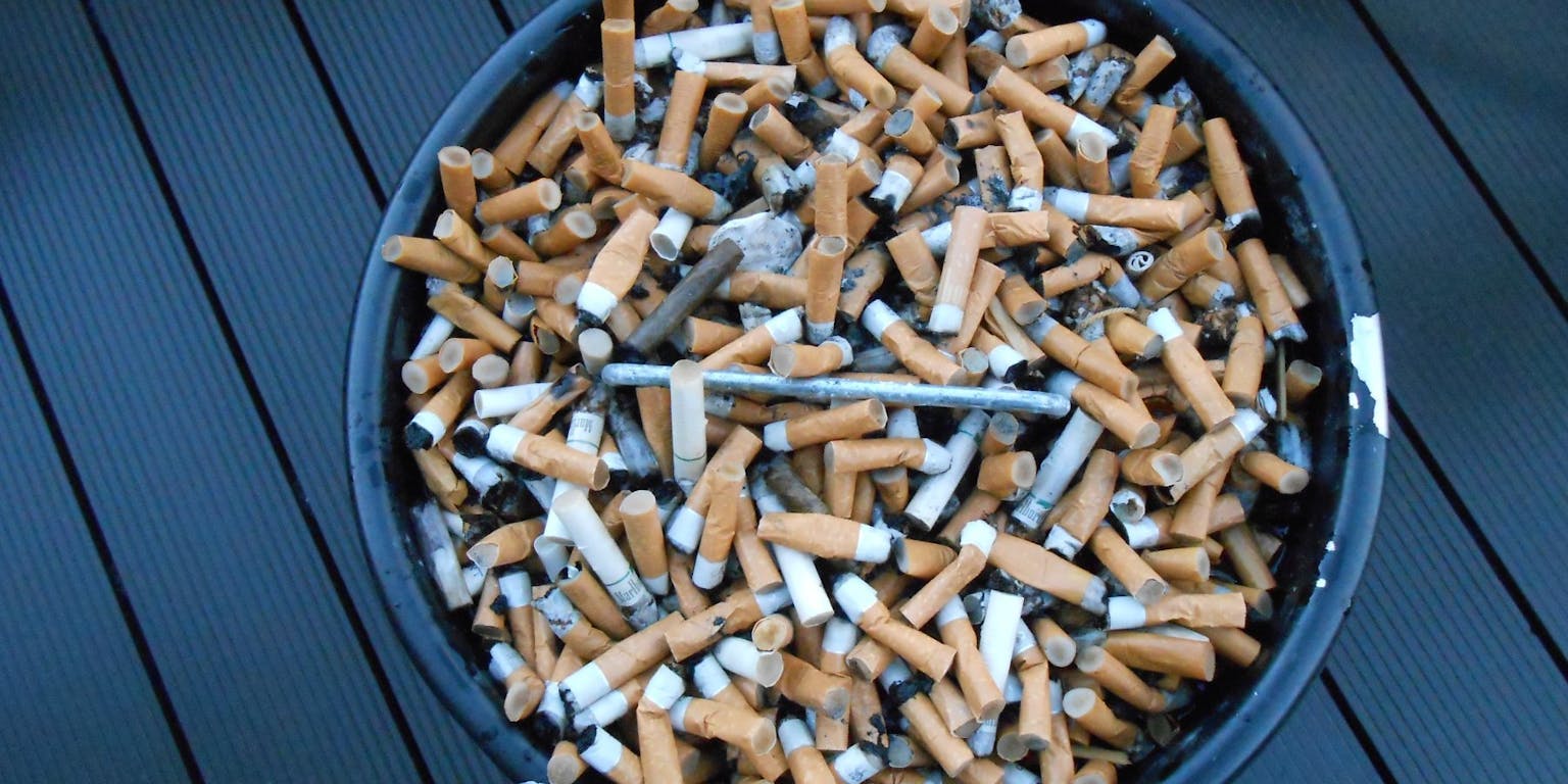 Een emmer vol sigaretten op een houten dek.