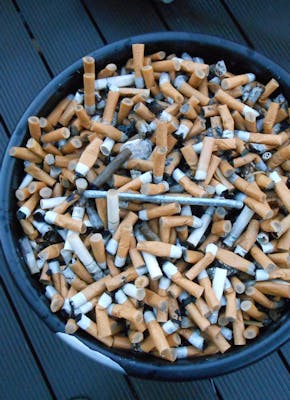Een emmer vol sigaretten op een houten dek.