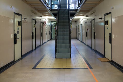 Gang van een moderne gevangenis, met in het midden een trap naar boven en langs beide zijkanten celdeuren. Gang van een moderne gevangenis, met in het midden een trap naar boven en langs beide zijkanten celdeuren.