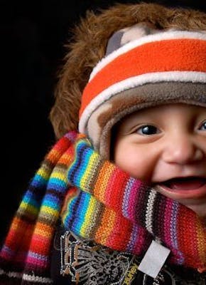 Een baby met een kleurrijke muts en sjaal.