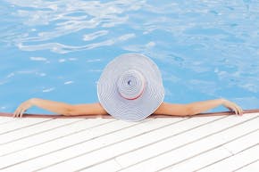 Een vrouw met een hoed in een zwembad.