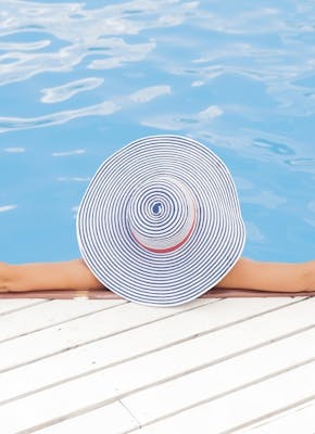 Een vrouw met een hoed in een zwembad.