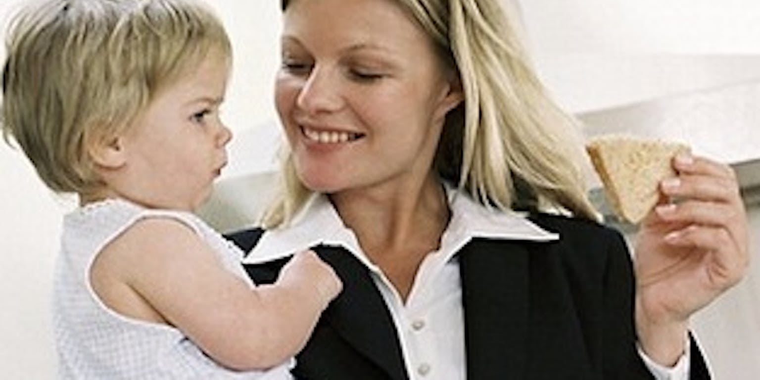 Een vrouw houdt een baby vast en eet een broodje.