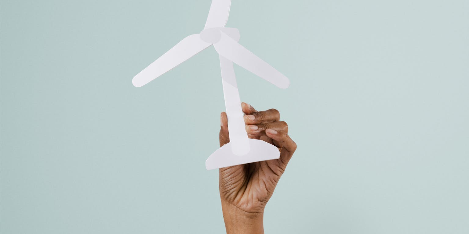 Een hand houdt een miniatuur windmolen vast