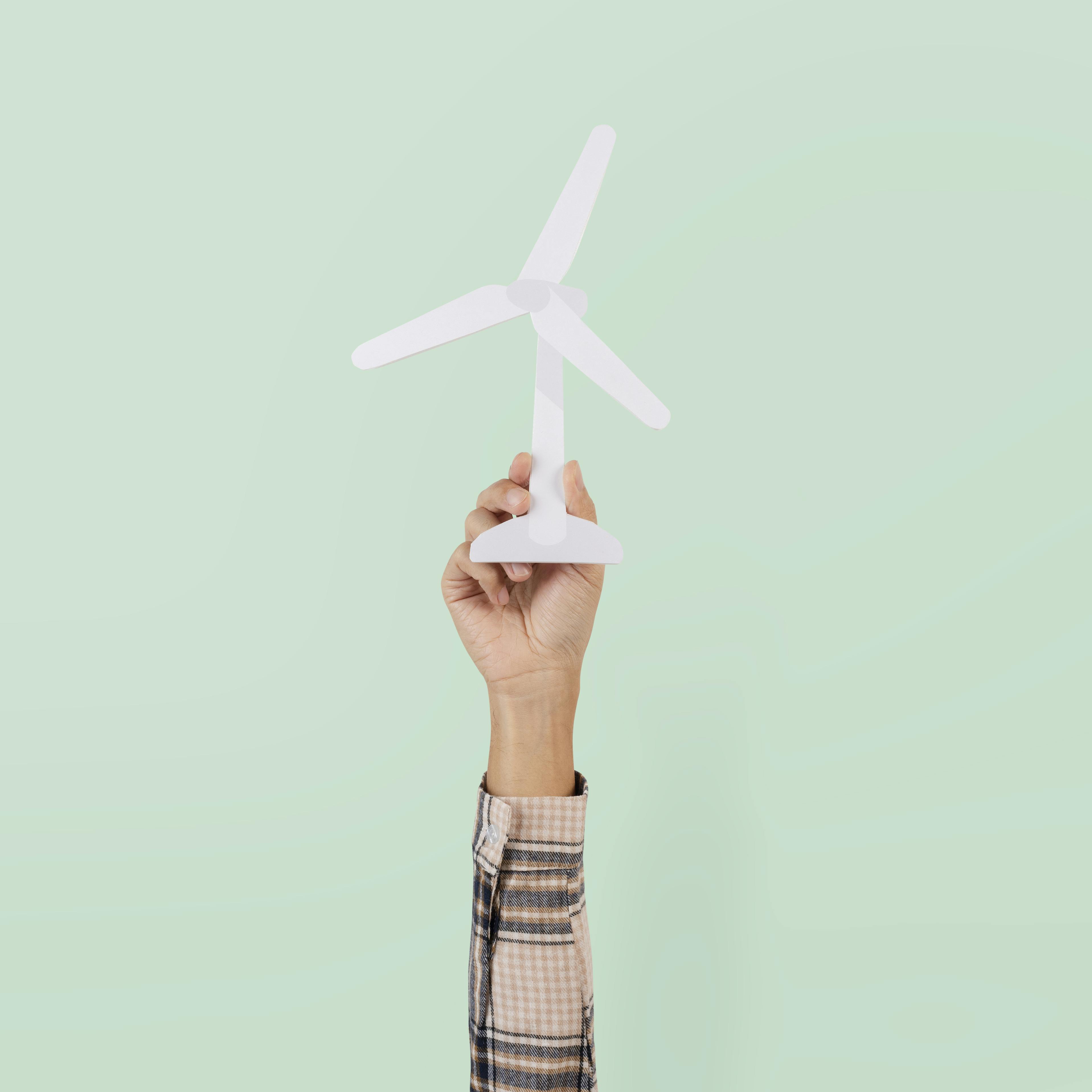 Een hand houdt een miniatuur windturbine vast