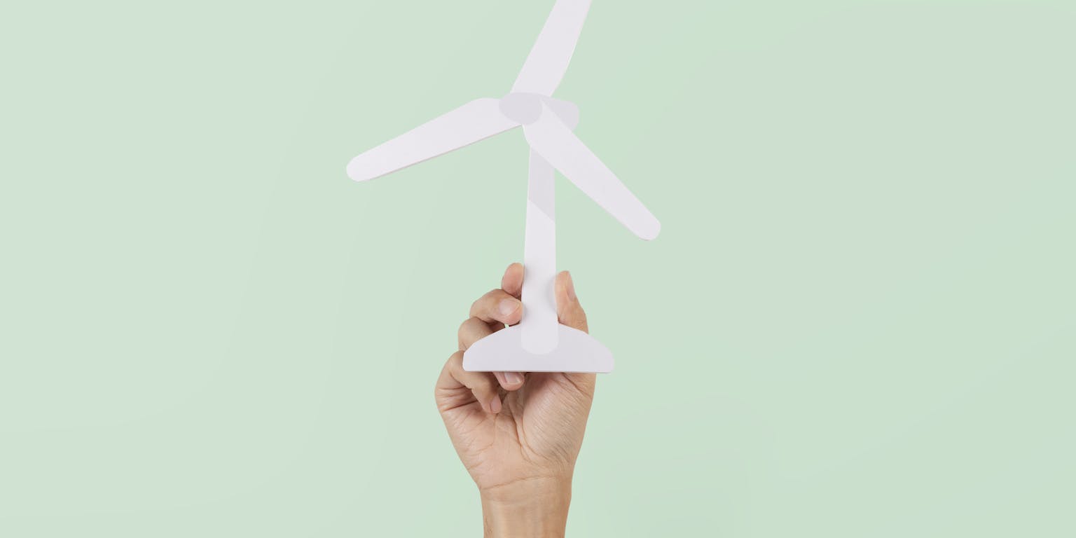 Een hand houdt een miniatuur windturbine vast