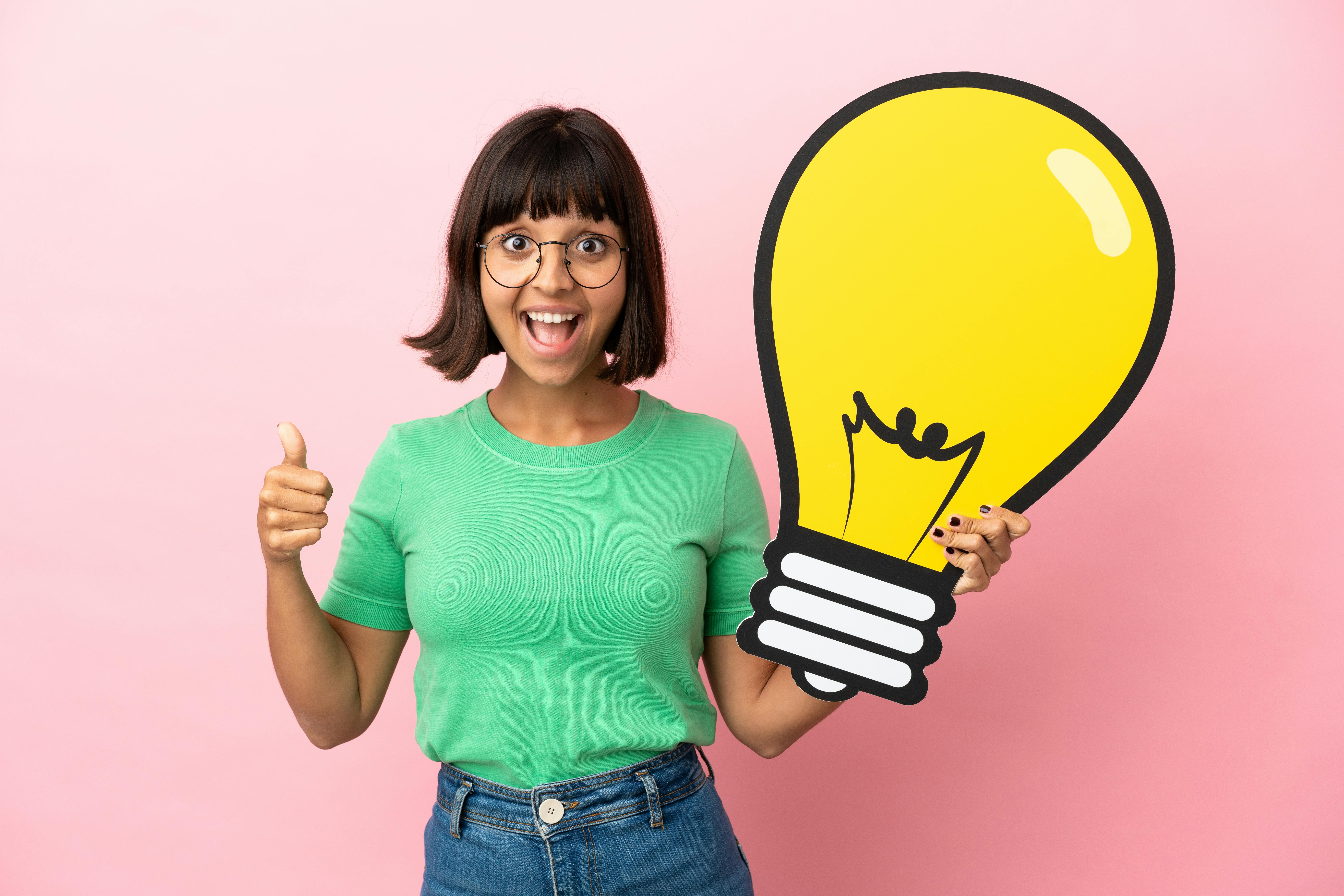 Jonge vrouw houdt idee vast in de vorm van een gloeilamp en kijkt blij