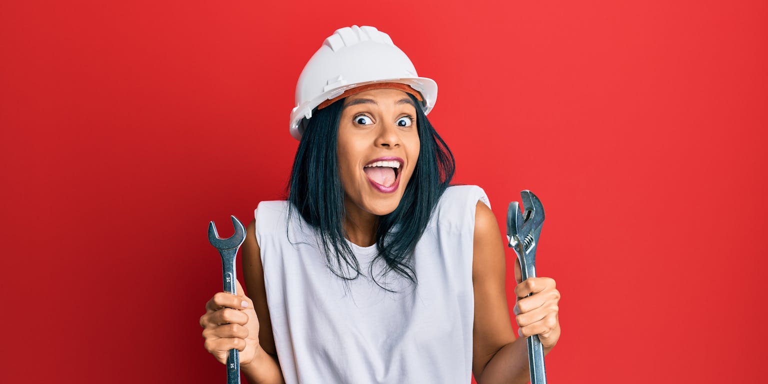 Vrouw met witte helm op kijkt blij met twee waterpomptangen in haar beide handen